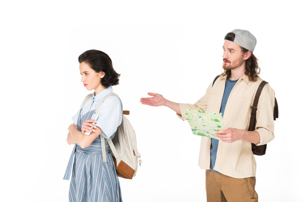 joven hombre sosteniendo mapa en las manos, tratando de hablar con chica ofendida aislado en blanco
 - Foto, Imagen