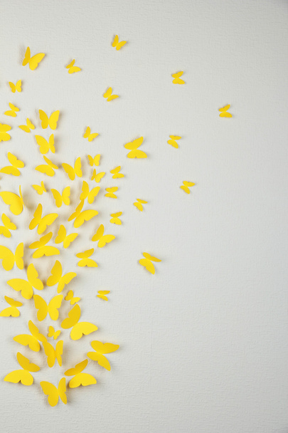 Paper yellow butterflies fly on wall in different directions - Photo, image