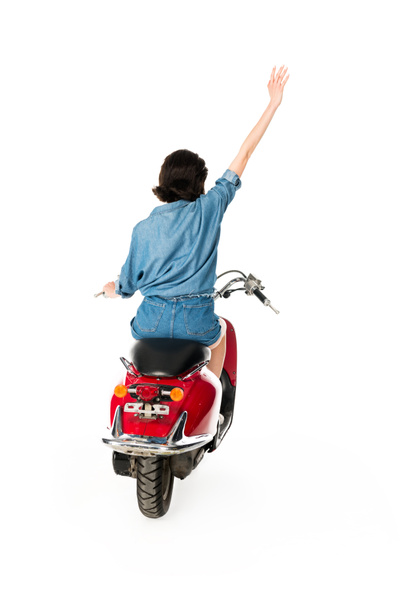 back view of girl with hand in air sitting on red scooter isolated on white - Фото, изображение