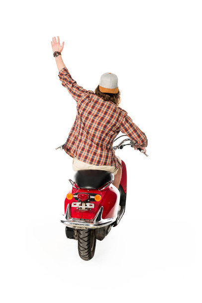 back view of young man with hand in air sittting on red scooter isolated on white - Foto, Bild