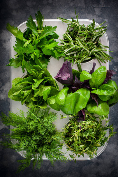 Various spicy fresh herbs: basil, thyme, dill, parsley, rosemary in metallic form, top view, selective focus - Photo, Image