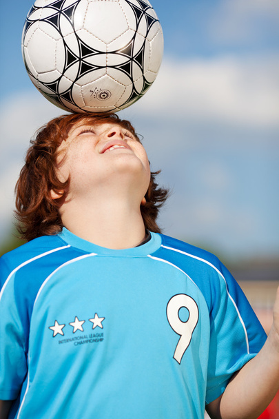 boy balancing soccer ball on his head - Valokuva, kuva