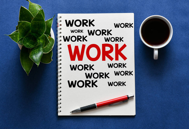 Ansicht des Arbeitsplatzes mit Schriftzeichen auf Notizblock, Tasse Kaffeemaschine und grüner Pflanze auf blauem Hintergrund  - Foto, Bild
