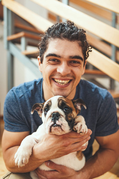 Feliz joven sonriente con perrito bulldog en nuevo apartamento
  - Foto, Imagen