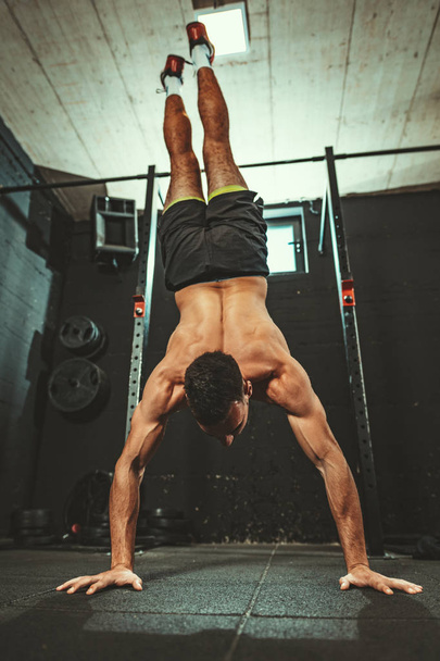 muskularny młody człowiek robi Handstand ćwiczenia w CrossFit treningu - Zdjęcie, obraz