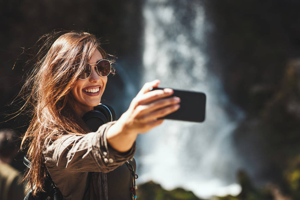 Happy woman enjoying landscape and making selfie in mountains  - 写真・画像