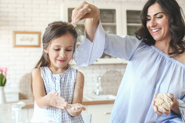 Happy mother with daughter preparing cookies in kitchen at home - Photo, Image