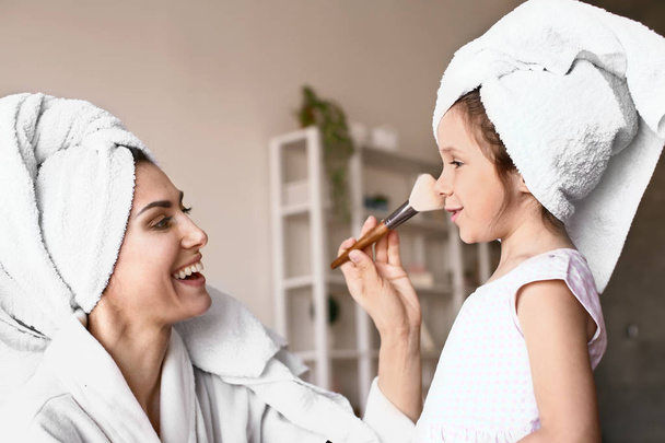 Moeder met schattige dochter doen make-up thuis - Foto, afbeelding