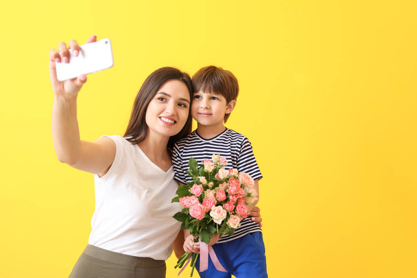 Happy mother and son taking selfie on color background - Photo, Image