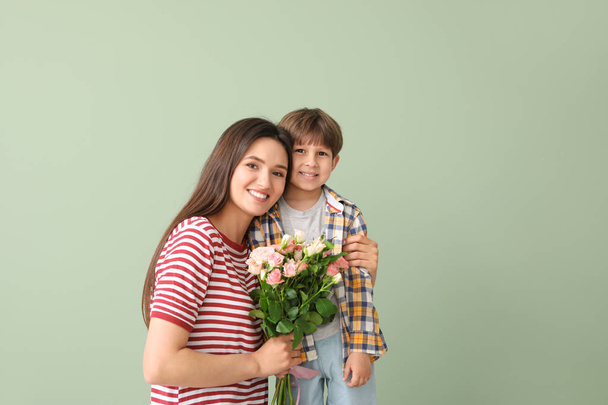Happy mother and son with bouquet of flowers on color background - Photo, Image