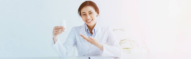 Панорамный снимок улыбающегося латинского врача, указывающего рукой на контейнер с таблетками
 - Фото, изображение