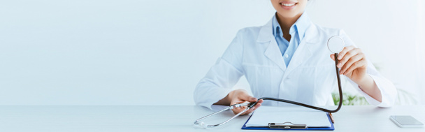 panoramatický záběr usmívajícího se lékaře s stetoskem blízko schránky - Fotografie, Obrázek