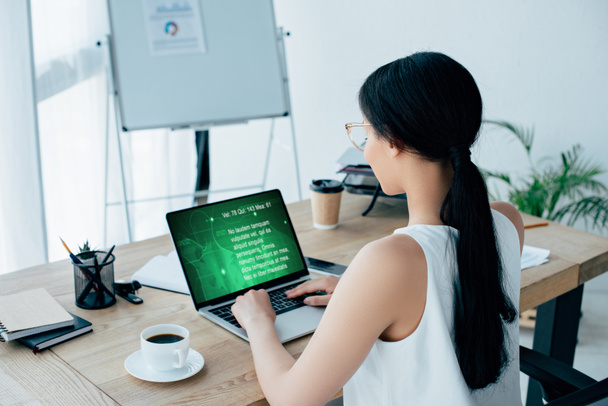 młoda latynoska bizneswoman za pomocą laptopa z informacji tekstowych na ekranie podczas siedzenia w miejscu pracy w pobliżu filiżanki kawy - Zdjęcie, obraz