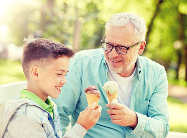old man and boy eating ice cream at summer park - Foto, afbeelding