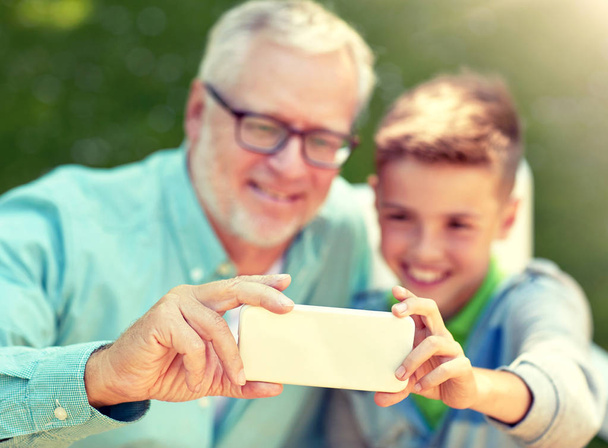 old man and boy taking selfie by smartphone - Фото, зображення