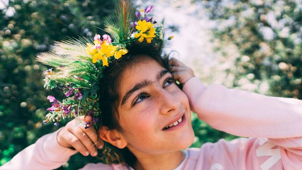 Portrait of a beautiful little girl wearing floral wreath. - Фото, изображение