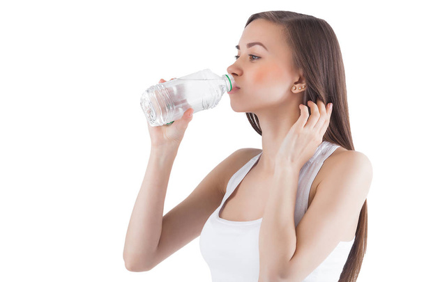attraktive junge Frau, die Wasser auf isoliertem weißen Hintergrund trinkt. Weibchen halten Flasche Wasser. - Foto, Bild