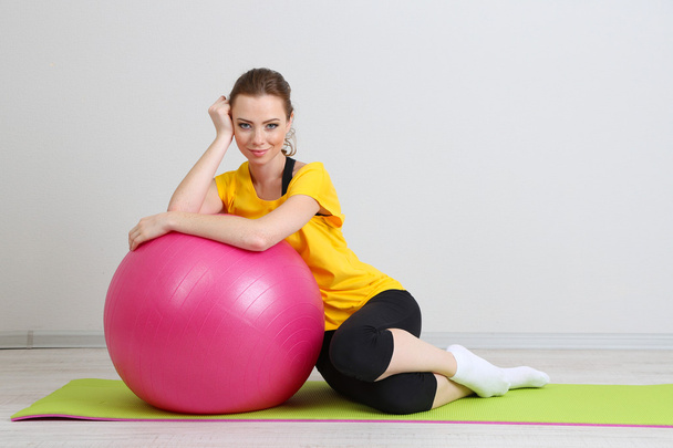 Portrait of beautiful young woman exercises with gym ball - Фото, изображение