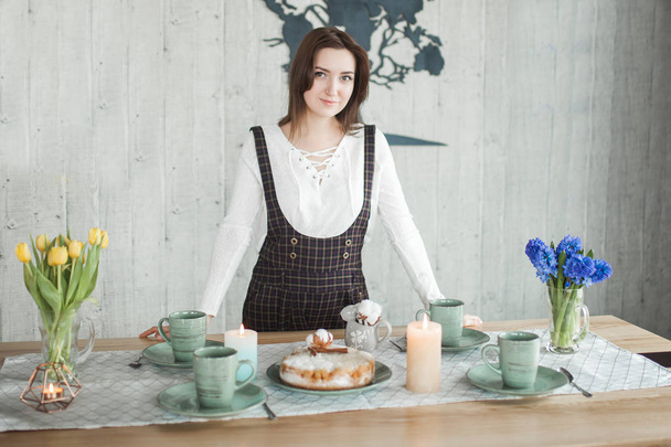 Νεαρή νοικοκυρά στο τραπέζι. Γυναίκα με πίτα Σαρλότ. Γυναίκα στην κουζίνα της σοφίτας. Η κυρία πίνει τσάι με μηλόπιτα. - Φωτογραφία, εικόνα