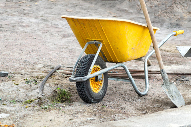 Kolečko. Žlutý vozík na stavbu. Použití peří, kamení, písku, cementu. - Fotografie, Obrázek