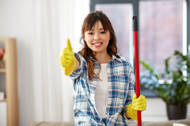 asiático mujer limpieza casa y mostrando pulgares hasta
 - Foto, imagen