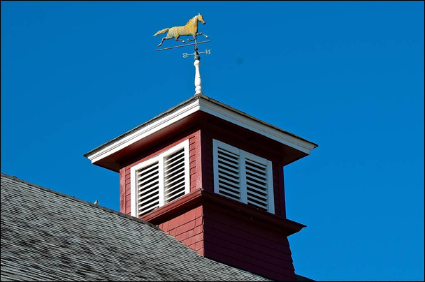 Una cupola in un fienile di un ranch mostra una banderuola con un trotto di cavallo
.  - Foto, immagini
