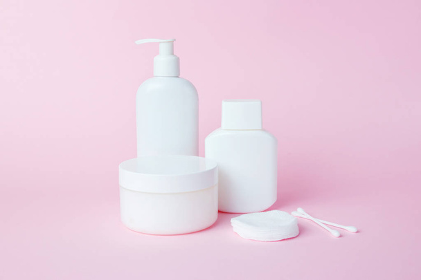 White jars of cosmetics on a pink background. Bath accessories. Face and body care concept - 写真・画像