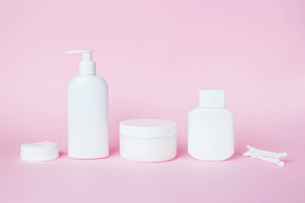 Frascos blancos de cosméticos sobre un fondo rosa. Accesorios de baño. Concepto de cuidado facial y corporal
 - Foto, imagen