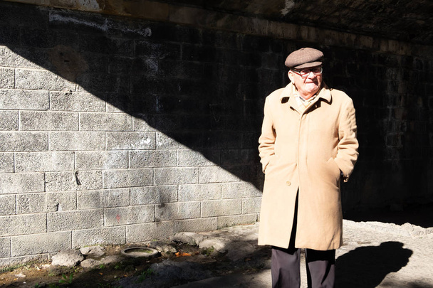 Sicily, Italy - January 21, 2016: Unknown old man in traditional wear passes under the bridge at local park this morning in Catania. - Photo, Image