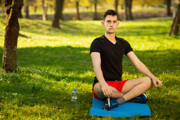 Un joven haciendo yoga en el parque verde. Concepto de un estilo de vida saludable
 - Foto, imagen