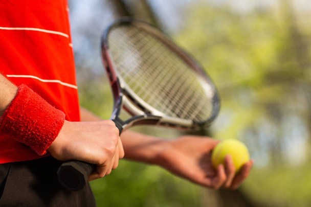 Erkeklerin ellerini yakın tutarak yeşil arka planda bir tenis raketi ve top tutun. Spor konsepti - Fotoğraf, Görsel