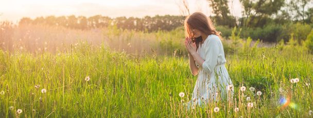 Dziewczyna zamknęła oczy, modląc się w pole podczas pięknego zachodu słońca. Ręce składane w koncepcji modlitwy wiary - Zdjęcie, obraz