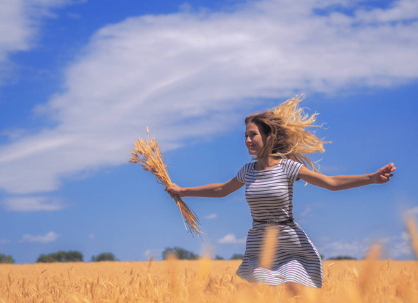 Młoda kobieta na polu pszenicy pod błękitnym niebem w słońcu - Zdjęcie, obraz