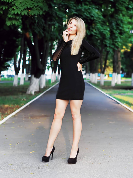 Young blonde girl staying at the park full size and looking at t - 写真・画像