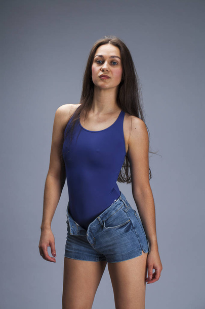 Brunette woman in blue bathing suit and jeans shorts posing in t - Foto, immagini