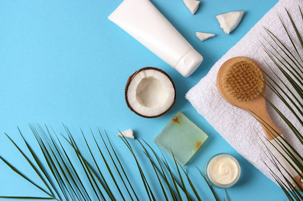 Coconut, tropical leaf and care products on a colored background top view. Cosmetics with coconut extract for hair, body, face. Skin care, skin hydration. flatlay - 写真・画像