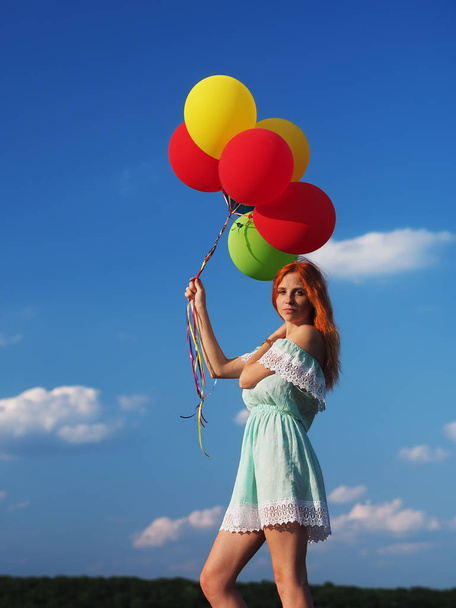 Młoda ruda dziewczyna z kolorowe balony stojące na niebieskim s - Zdjęcie, obraz