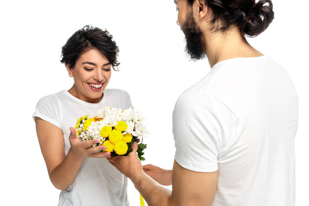 bearded man giving flowers to happy latin woman isolated on white  - Fotó, kép