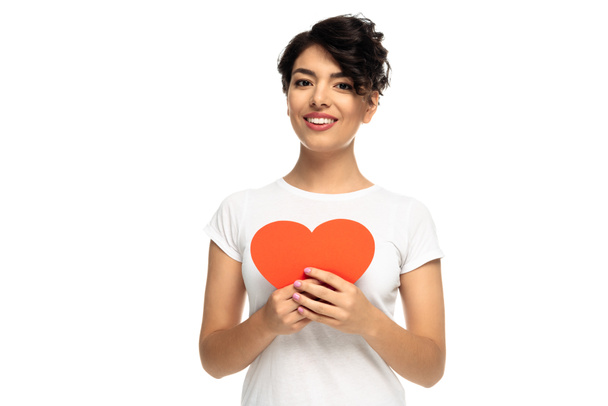 cheerful latin woman holding red heart-shape carton isolated on white  - Fotó, kép