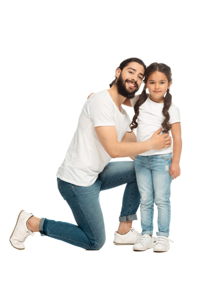 szczęśliwy Łacina ojciec uśmiechnięty podczas przytulanie słodkie córka na białym tle  - Zdjęcie, obraz