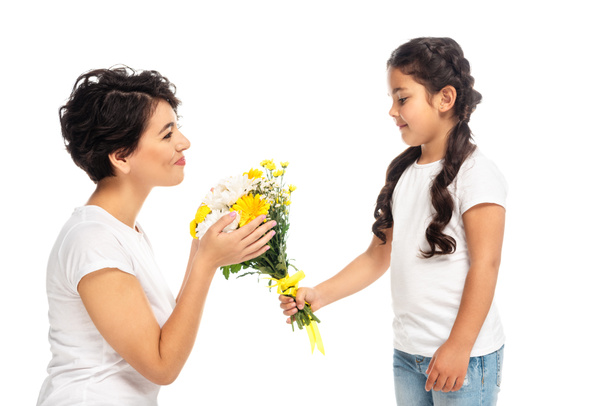 ευτυχισμένο παιδί δίνοντας λουλούδια σε ελκυστική Λατινική μητέρα απομονώνεται σε λευκό  - Φωτογραφία, εικόνα