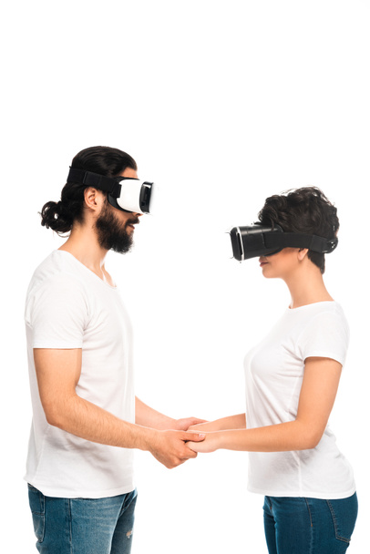 χαρούμενο Λατίνο ζευγάρι κρατώντας τα χέρια φορώντας ακουστικά εικονικής πραγματικότητας απομονώνονται σε λευκό  - Φωτογραφία, εικόνα