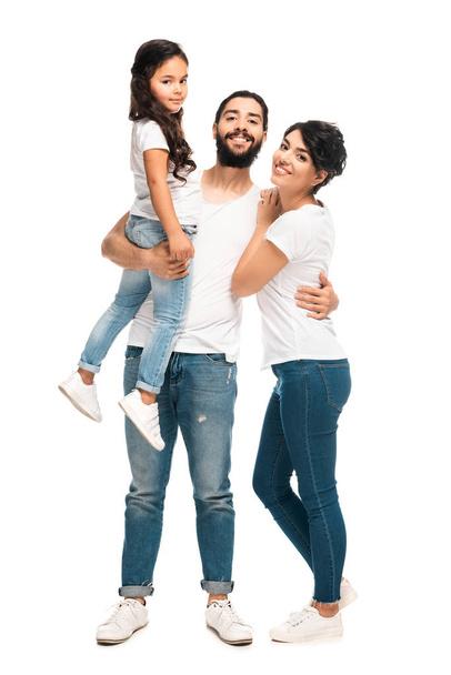 白に孤立した妻と一緒に立っている間、腕のかわいい娘を抱きしめる幸せなラテン人  - 写真・画像
