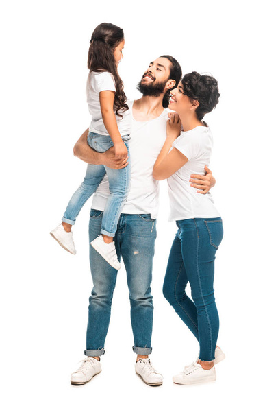 Gelukkig Latijnse man holding in Arms schattige dochter terwijl staand met aantrekkelijke vrouw geïsoleerd op wit  - Foto, afbeelding