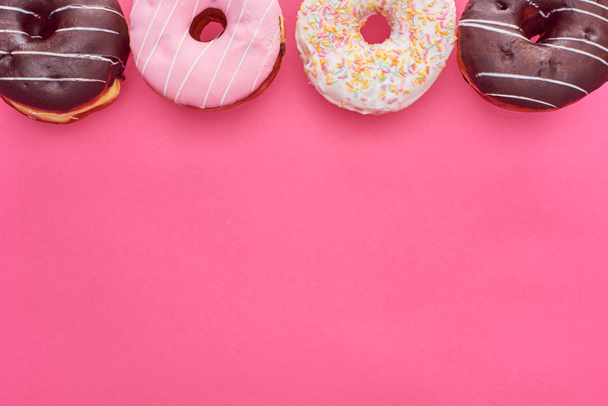top view of delicious glazed doughnuts on bright pink background with copy space - Foto, Imagem