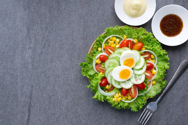Healthy vegetables salad with boiled egg in wooden dish on table - Photo, Image
