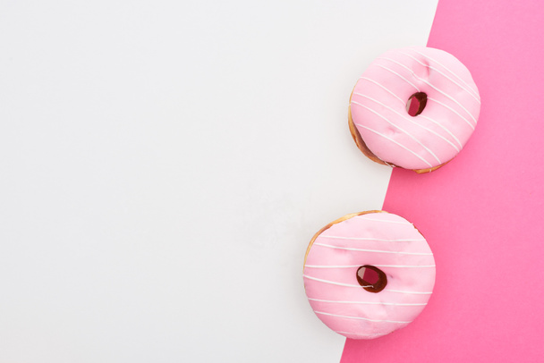 top view of glazed pink doughnuts on white and pink background with copy space - Φωτογραφία, εικόνα