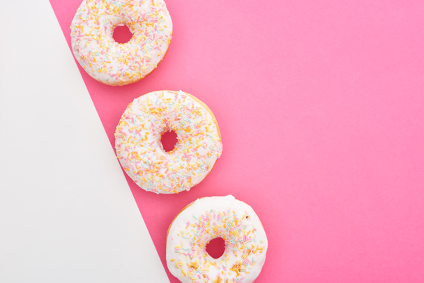 top view of tasty glazed doughnuts on white and pink background with copy space - Photo, Image