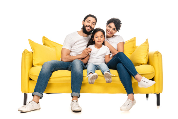 happy latin parents smiling while sitting on sofa with adorable daughter isolated on white  - Foto, immagini