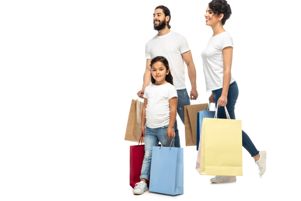 genitori latini felici in possesso di borse della spesa mentre in piedi con il bambino isolato su bianco
   - Foto, immagini